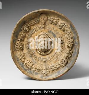 Bol en terre cuite phiale (libération). Culture : l'étrusque. Dimensions : H. : 1 3/4 in. (4,4 cm) Diam. : 9 5/16 in. (23,7 cm). Date : ca. 250-200 av. J.-C.. L'argile avec ornements en relief : tête de silène en centre ; reste de pigments bleu et jaune. Musée : Metropolitan Museum of Art, New York, USA. Banque D'Images