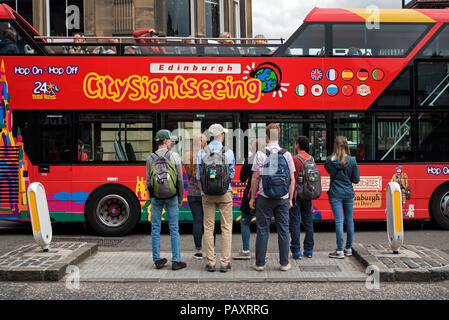 Edinburgh bus de tourisme en passant d'un groupe de touristes attendant de traverser la route à Édimbourg, Écosse, Royaume-Uni. Banque D'Images