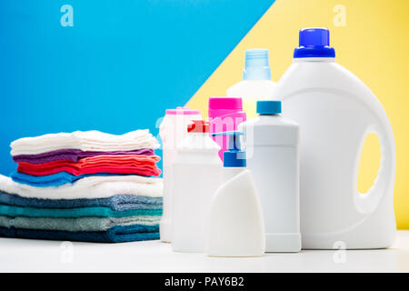 Photo de plusieurs bouteilles de produits de nettoyage et les serviettes de table de couleur blanc sur isolé sur fond jaune, bleu, lieu d'inscription Banque D'Images