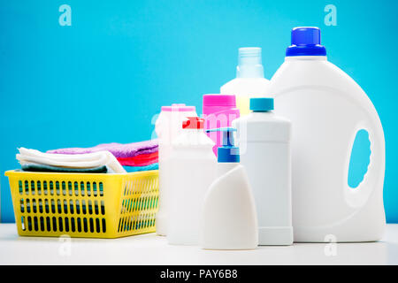 Photo de plusieurs bouteilles de produits de nettoyage et les serviettes colorées dans panier isolé sur fond bleu, lieu d'inscription Banque D'Images