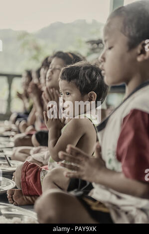 Les jeunes enfants disant leurs prières avant un repas à l'Orphelinat de Sangkhlaburi. Kanchanaburi. Thaïlande Banque D'Images