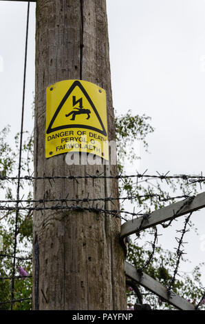 Panneau d'avertissement de danger de mort monté sur un transformateur d'électricité post de soutien. Le signe est au-dessus des barbelés. Le texte est en français et l'espèce d'Wel Banque D'Images