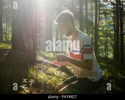 Portrait de jeune homme dans la forêt de remue-méninges avec bloc-notes papier prise de notes concept éducation Banque D'Images