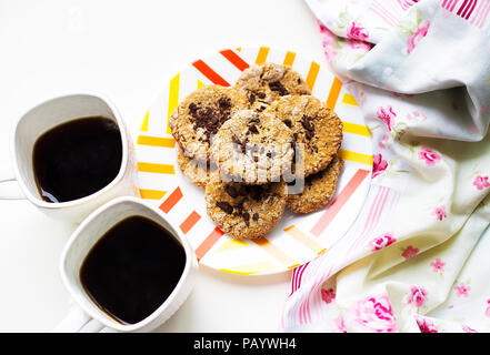 Oatmeal Cookies au chocolat sur une plaque recouverte de tissu lumineux et deux tasses de café Banque D'Images