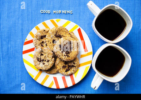 Oatmeal Cookies au chocolat sur fond bleu serviette et deux tasses de café, bonjour l'inscription Banque D'Images
