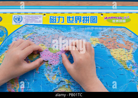 China-April,Zhongshan 15,2018:kid jouer puzzle carte du monde et de mettre la Chine dans la position correcte. Banque D'Images