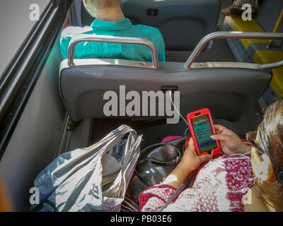 Un passager d'un bus bus Service select sur la route M23, à Chelsea, à New York, le samedi 14 juillet 2018, prises européennes son smartphone dans un port USB. NYCTA Président Andy Byford a récemment annoncé le Plan d'Action 'BUS', une refonte complète du système de transport de surface de la ville y compris l'introduction d'autobus à deux étages, l'augmentation de la capacité de payer avant l'embarquement et d'une app pour vérifier si les sièges sont disponibles. Le nombre de bus est tombé dans la ville. (Â© Richard B. Levine) Banque D'Images