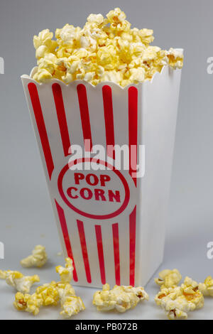 Un déshabillé rouge petit seau de popcorn popcorn débordant de sur un compteur blanc Banque D'Images