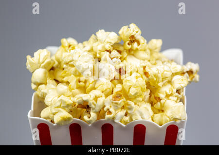 Un déshabillé rouge petit seau de popcorn popcorn débordant de sur un compteur blanc Banque D'Images