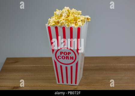 Un déshabillé rouge petit seau de popcorn popcorn débordant de sur un compteur blanc Banque D'Images