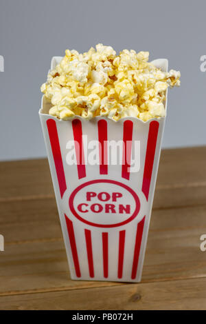 Un déshabillé rouge petit seau de popcorn popcorn débordant de sur un compteur blanc Banque D'Images