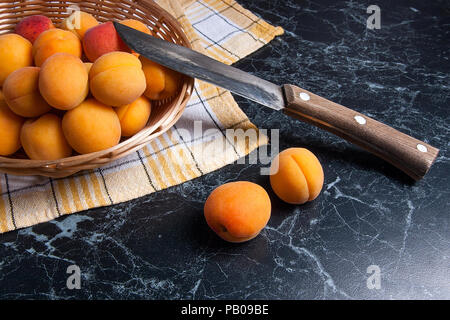 Organique mûres les abricots dans le panier en bois jaune. Composition dans un style rustique - organic red juicy les abricots dans le panier en bois vintage et vintage couteau sur Banque D'Images