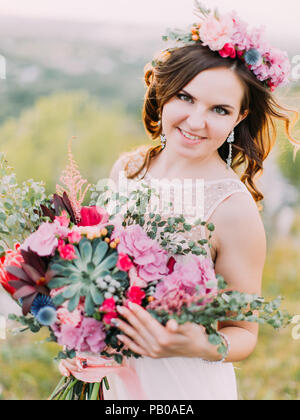 La vue rapprochée de l'smiling bride holding l'énorme bouquet de mariage. Banque D'Images