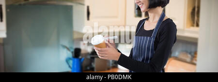 Image composite de smiling waitress écrit sur la tasse de café à usage unique Banque D'Images