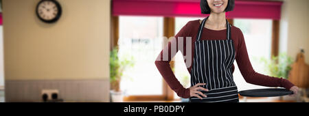 Image composite de smiling waitress holding bac vide contre fond blanc Banque D'Images