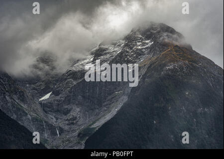 MISTY, montagne, ciel nuageux, LA LUMIÈRE DU SOLEIL, LA NEIGE, l'eau des cascades. Les nuages brumeux flotter au-dessus de la montagne enneigée haut avec jets d'eau en cascade. Banque D'Images