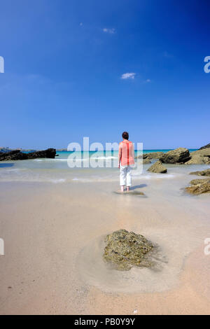 Femme debout dans l'eau peu profonde sur une belle plage à Cornwall Banque D'Images