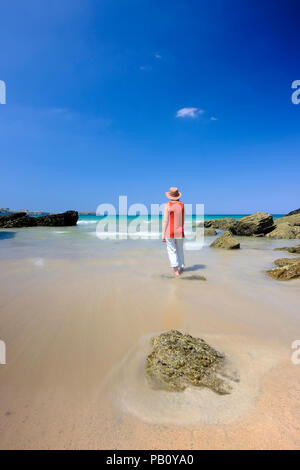 Femme debout dans l'eau peu profonde sur une belle plage à Cornwall Banque D'Images