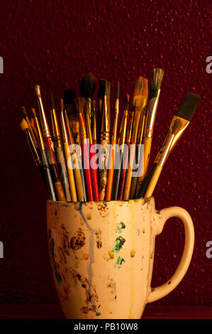 Pinceaux multicolores dans une tasse à café, toujours sous la lumière du soleil. Banque D'Images