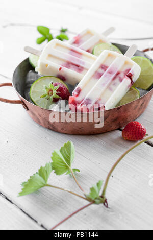 Les sucettes glacées faites avec des fraises et citron vert Banque D'Images