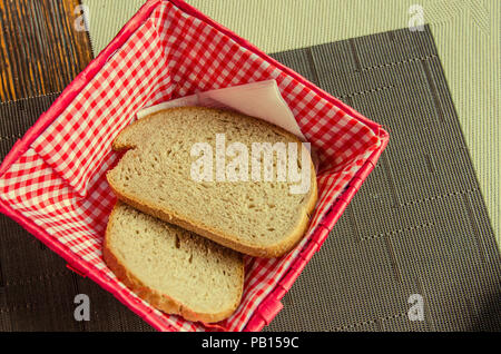 Deux morceaux de pain dans une belle boîte à pain sur une table dans un café. Du pain frais, sur du papier blanc en boîte du pain sur table en bois avec arrière-plan Banque D'Images