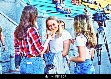 Les jeunes joueurs et jolie femelle American football cheerleaders at stade Spartak Kiev (Ukraine) profiter d'une collation rapide entre les jeux des hommes Banque D'Images