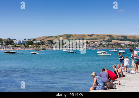 Les gens assis sur la promenade à côté de la baie de Swanage, le soleil brille, par temps chaud et un dimanche après-midi de juillet 2018 Banque D'Images