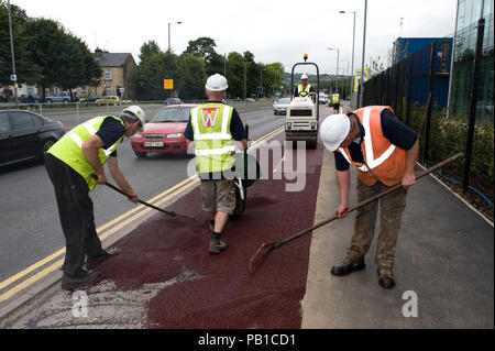 Ashphaltfrom ouvriers verser une brouette et portant sur l'asphalte rouge à la route, au Royaume-Uni Banque D'Images