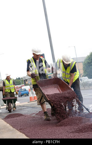 Ashphaltfrom ouvriers verser une brouette et portant sur l'asphalte rouge à la route, au Royaume-Uni Banque D'Images