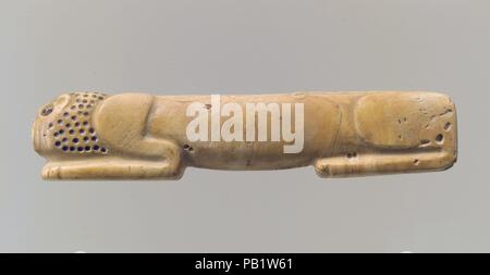 Amulette en forme de lion couchant. Dimensions : 7/8 x 4 1/8 in. (2,2 x 10,6 cm). Date : ca. 2900-2700 av. J.-C.. Ce petit objet sculpté dans un morceau de coquille représente un lion couché avec la tête posée sur ses pattes avant. Les éléments de l'animal sont modélisés de façon très simple : hanches, le corps, les épaules et les pattes avant, et la tête peuvent être identifiés. Le dos est droit et le ventre pend légèrement. Les petits trous percés marquer la crinière, et plus grands trous indiquent l'œil et l'oreille. Des traces de pigment dans ces trous donnent à penser qu'ils ont initialement été incrusté d'un matériel dans une couleur contrastante. Lio Banque D'Images