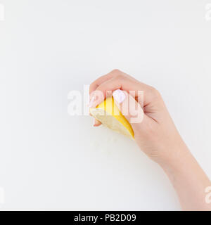 Femme part avec manucure pastel polish tenant une moitié de citron isolé sur fond blanc copie espace style minimaliste. Modèle carré pour le féminin Banque D'Images