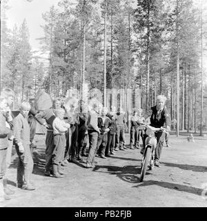 Adolescent mâle équitation un cyclomoteur motocyclette regardé par les garçons sur un voyage de camping dans la campagne, Saarijärvi, Finlande, 1959 amerique Banque D'Images