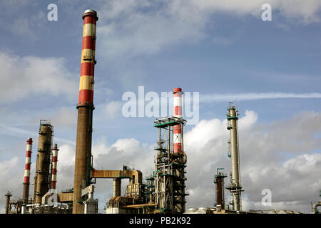 Partie d'une grande raffinerie de pétrole avec beaucoup de rouge et de blanc dans une cheminée en fin d'après-midi nuageux Banque D'Images