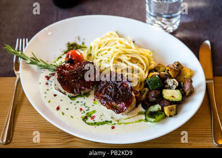 Plat au restaurant Bühlberg. Médaillons de porc en laque de viande sèche Lenk avec de fines nouilles sur la sauce Lenk Berg Bleu Banque D'Images