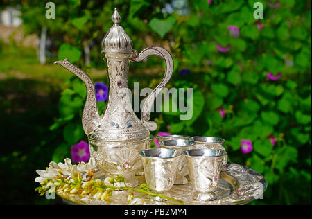 Ancienne carafe et verres d'argent et de feuilles vertes sur fond Banque D'Images