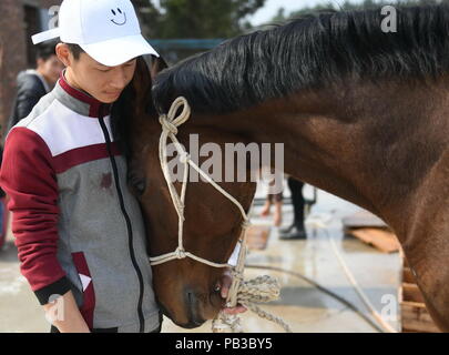 (180726) -- NANCHANG, le 26 juillet 2018 (Xinhua) -- Huang Wanpeng, un étudiant de Soleil Riding School, caresse un cheval blessé dans le Xian de de Fuzhou, Chine de l'est la province de Jiangxi, du 14 mars 2018. Rennes n'a jamais été entendu dans le Xian de, un comté agricole dans l'est de la Chine, la province de Jiangxi, jusqu'à l'École d'équitation du Soleil ont commencé à recruter des adolescents en milieu rural en 2015. Jusqu'à présent, la plupart des 90 élèves travaillent ou qui aspirent à travailler dans l'équitation clubs dans la plus grande des villes comme Beijing, Shanghai et Hangzhou. (Xinhua/Zhou Mi) (LMM) Banque D'Images