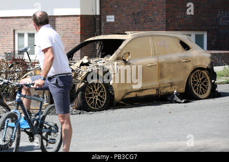 Hambourg, Allemagne. 26 juillet, 2018. Une carcasse de voiture brûlée de la marque Porsche pulvérisés avec de la peinture dorée se trouve sur la rue en Rainvilleterrasse Ottensen. La voiture, à l'instar de plusieurs autres véhicules, brûlé dans la nuit du 9 juillet 2018, un an après le G20 des émeutes. Les policiers enquêtent sur un incendie criminel. Credit : Bodo Marks/dpa/Alamy Live News Banque D'Images