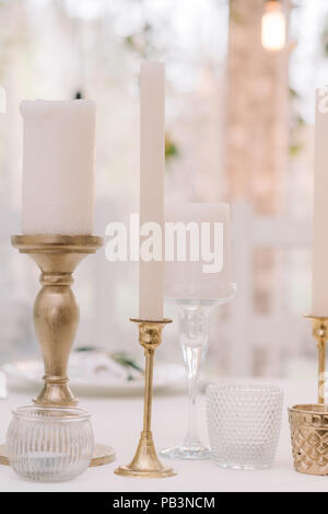 Les bougies blanches dans les chandeliers élégants de métal. La gamme de Bougeoirs et bougies sur une table de mariage Banque D'Images