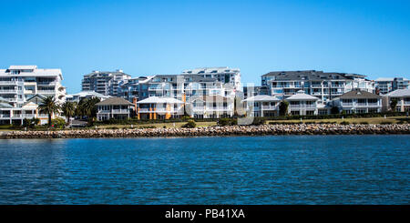 Maisons au bord de l'australien et condominiums avec rock sea wall against blue sky Banque D'Images