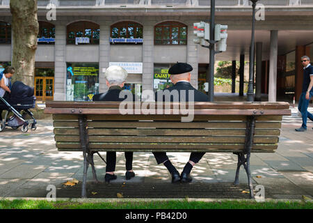 Basque Espagne, vue arrière d'un couple basque marié et senior assis ensemble sur un banc dans le centre de Bilbao, dans le nord de l'Espagne. Banque D'Images