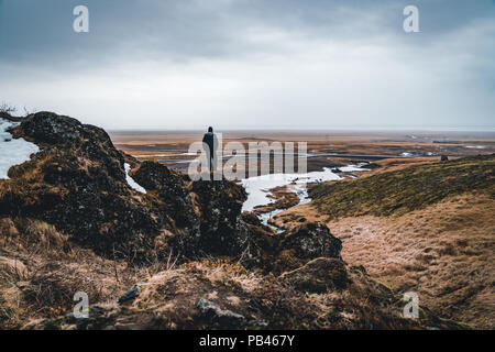 Jeune homme donnant sur la vue spectaculaire du matin célèbre Svartifoss (noir) Automne Cascade. Été haut en couleurs, le lever du soleil dans le parc national de Skaftafell Vatnajökull, l'Islande, l'Europe. Style artistique poste a traité la photo. Banque D'Images