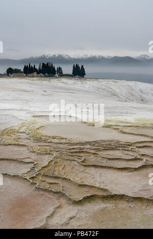 Une vue d'ensemble de terrasses en travertin de Pamukkale à quelques ruines et un groupe d'arbres avec une montagne en arrière-plan. Pamukkale, Turquie. Banque D'Images