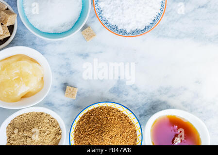 Différents types de Sucre et édulcorants dans les bols, tels que noix de coco, canne à sucre pur, le glaçage, le sirop d'érable, sucre mou brun foncé, miel, cubes démérara Banque D'Images