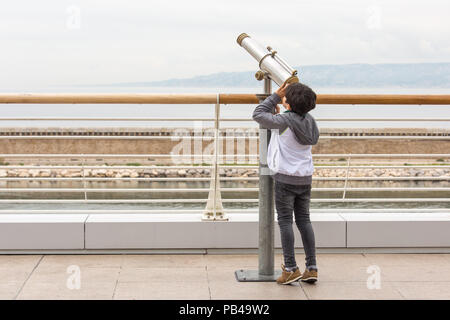 Un jeune garçon debout sur ses orteils, d'explorer le ciel avec un télescope Banque D'Images