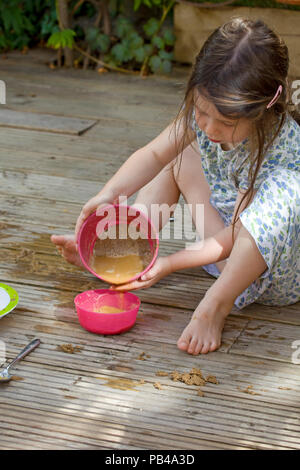 Young Girl making pies de sable à l'extérieur Banque D'Images