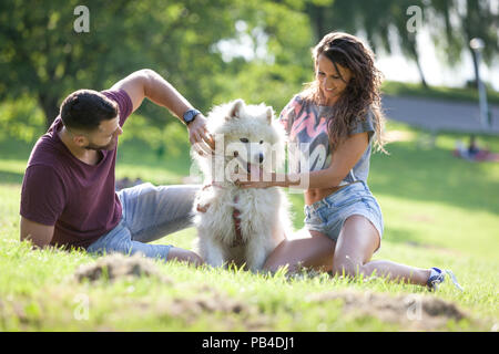 Joli jeune couple ayant le temps de qualité avec leur chien dans le parc. Banque D'Images