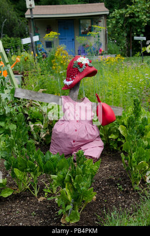 Épouvantail femelle avec un arrosoir et un chapeau de paille rouge dans le jardin communautaire de Yarmouth, Maine Banque D'Images