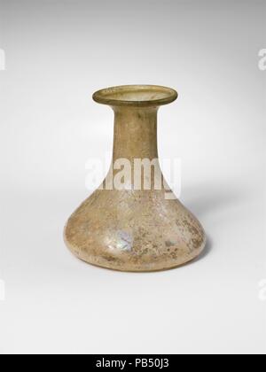 Bouteille en verre. Culture : Roman. Dimensions : H. : 2 13/16 in. (7,1 cm). Date : fin 1re, 3e siècle de notre ère. Incolore avec la teinte verte bleu et violet streak. Rebord, partiellement repliées et à lèvre épaisse, avec d'un côté, cylindrique à la base du cou, l'extension pour pouvoir rejoindre imperceptiblement à corps conique ; puis du côté des courbes au large, fortement ; bas avec creux circulaire autour du centre de télévision, patron. Intacts ; beaucoup de bulles et des impuretés ; irisé, altération blanchâtre couvrant la plupart des surfaces. Musée : Metropolitan Museum of Art, New York, USA. Banque D'Images