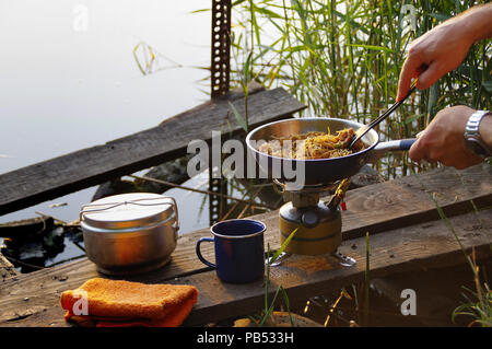 Camping de l'alimentation. Des pâtes sur le moule sur feu touristiques cuisinière. La cuisine du Camp sur la rive du lac. Banque D'Images