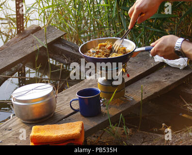 Camping de l'alimentation. Des pâtes sur le moule sur feu touristiques cuisinière. La cuisine du Camp sur la rive du lac. Banque D'Images